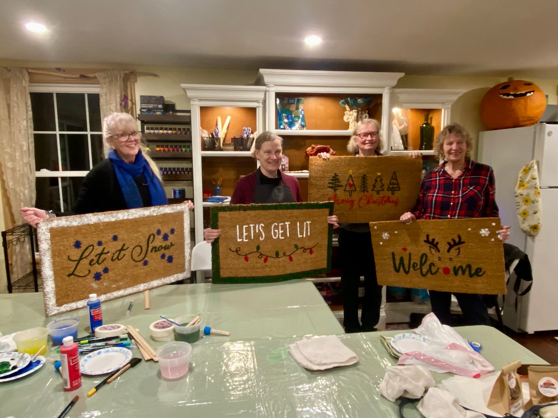 Friends holding painted Christmas doormats after a Craft Cottage class in Grafton NH