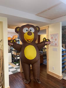 A person in a large brown inflatable bear costume posing in a doorway for the Let's Grow Grafton community fundraiser.