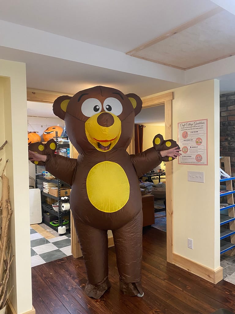 A person in a large brown inflatable bear costume posing in a doorway for the Let's Grow Grafton community fundraiser.